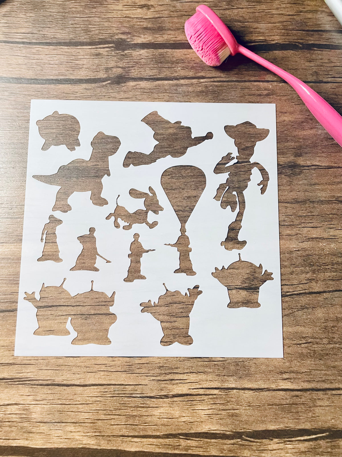 5.75” x 5.75” frosted stencil with Silhouettes of: piggy bank, dinosaur, flying space ranger, cowboy running, slinky dog, 4 army men, and 4 aliens 
