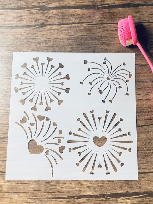 5.75” x 5.75” frosted stencil with Silhouettes of: four different fireworks with heart shaped sparks through them .  Stencil is on a wood surface with a pink brush 