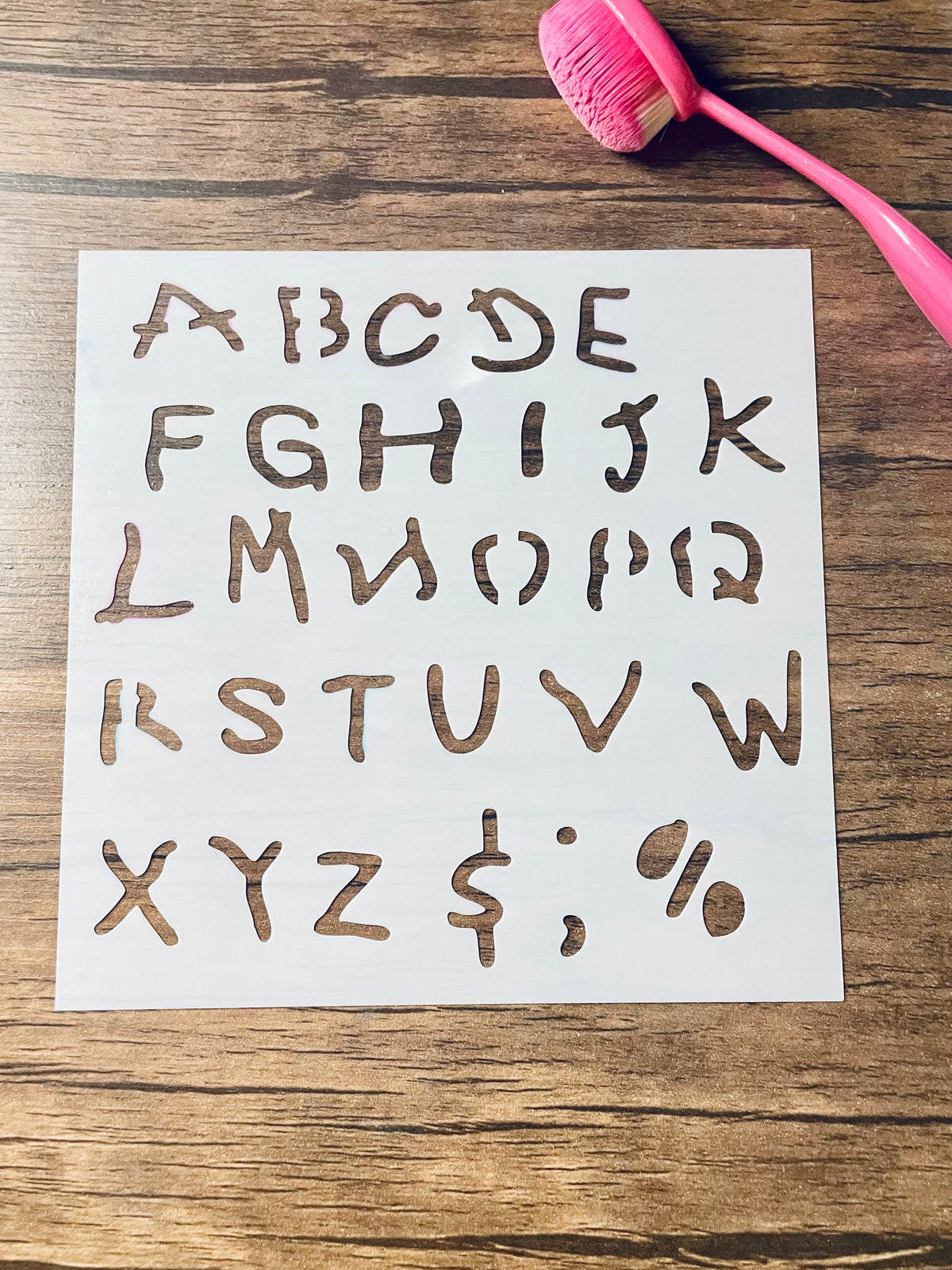 5.75” x 5.75” frosted stencil with Silhouettes of: The letters a-z in a roughly upper case font and $, ,, ., and % in a shaky child like writing 