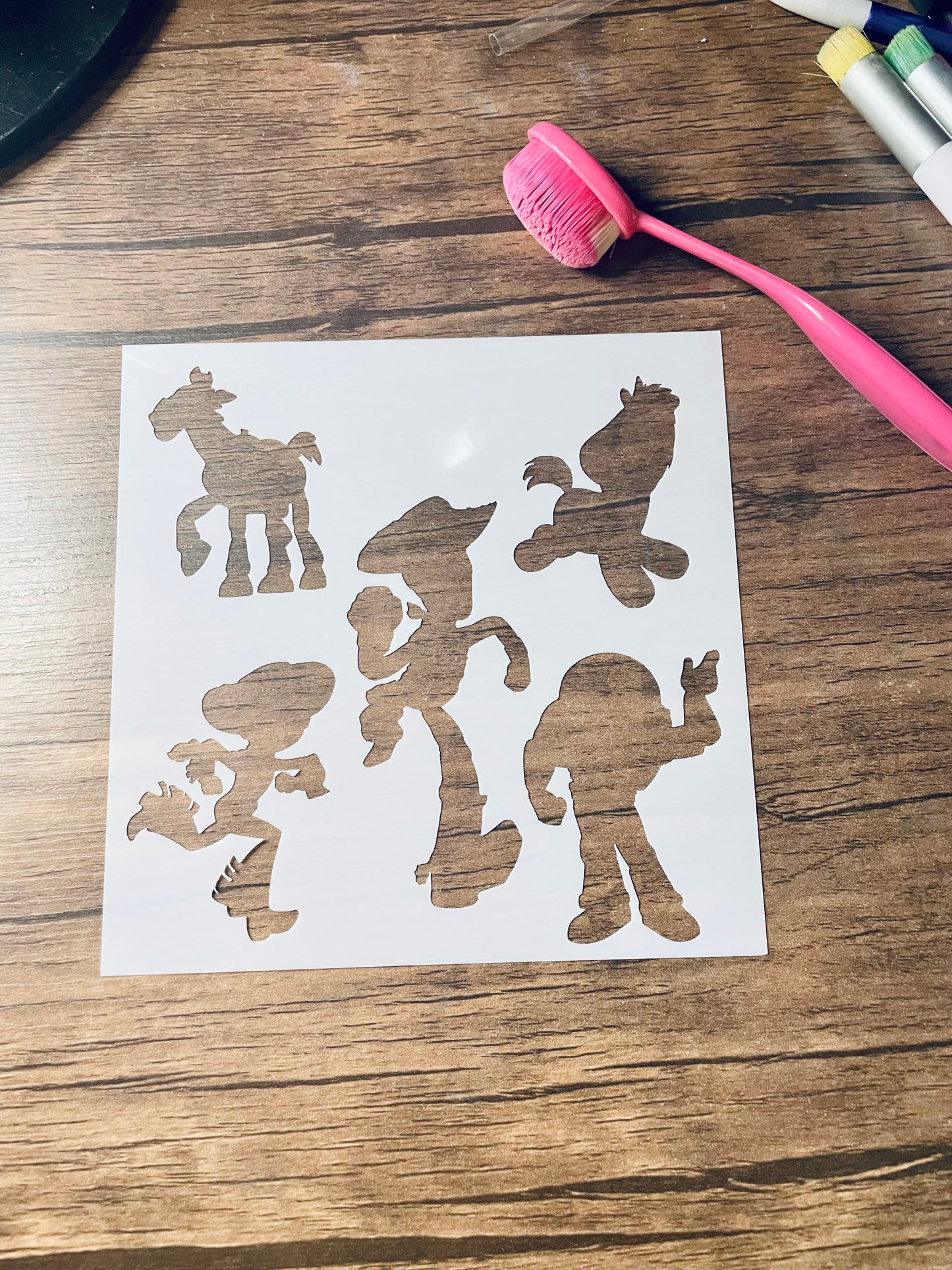 5.75” x 5.75” frosted stencil with five toy silhouettes including a cowboy running (twice), a space ranger waving, a plush unicorn and a toy horse. 