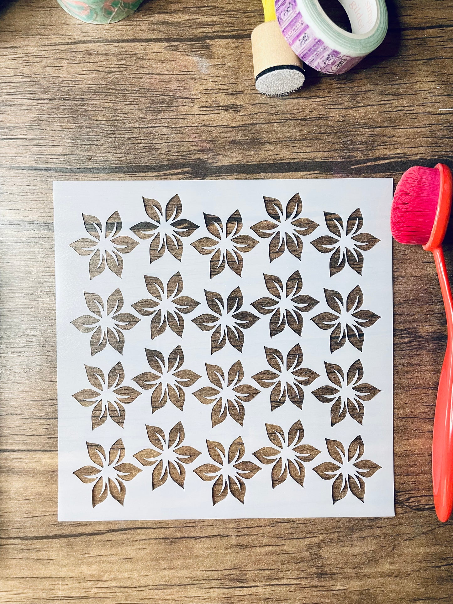 Floral patterned stencil on a wooden surface with a brush and washi tape