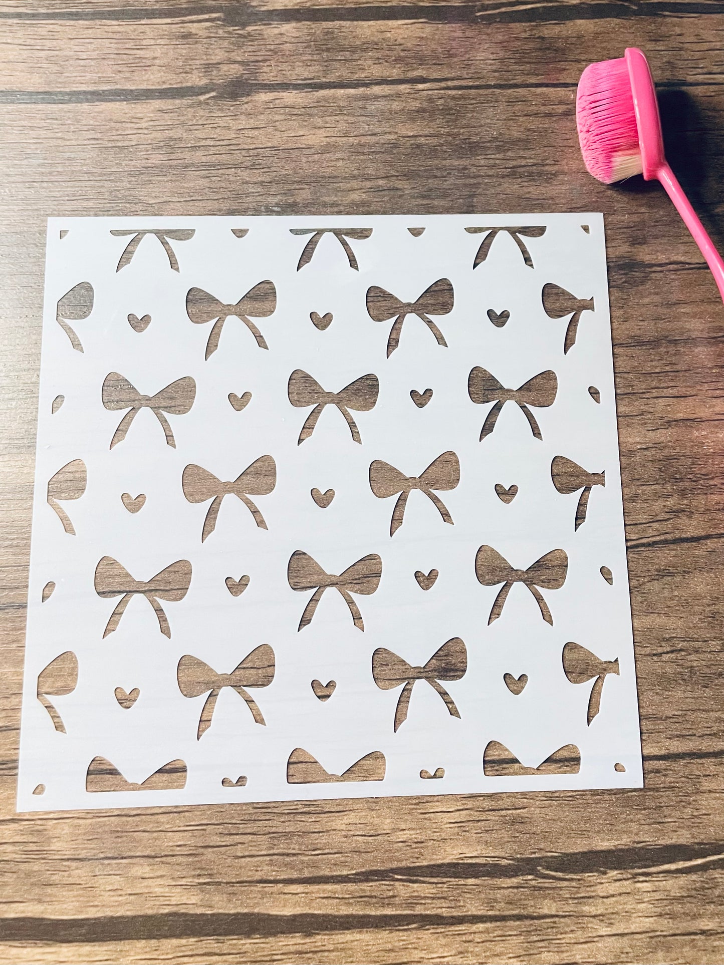 5.75” x 5.75” frosted stencil with Silhouettes of: Medium sized bows and tiny hearts in a pattern around the stencil 