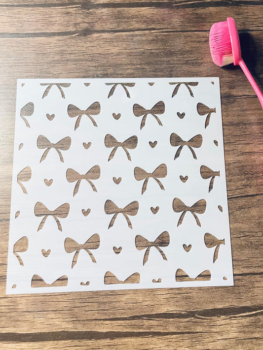 5.75” x 5.75” frosted stencil with Silhouettes of: Medium sized bows and tiny hearts in a pattern around the stencil 