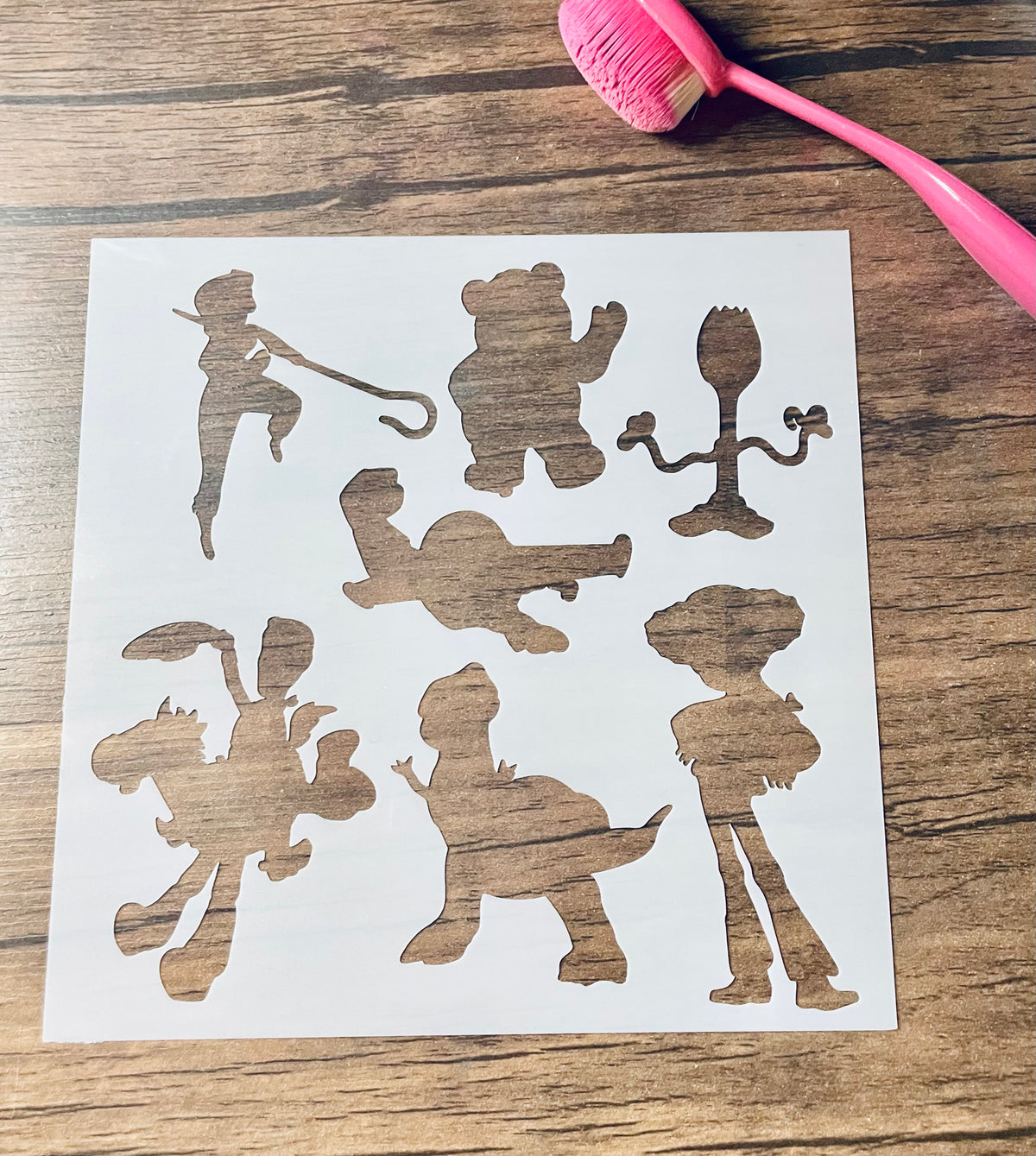 5.75” x 5.75” frosted stencil with silhouettes of: a bo peep doll, teddy bear, spoon toy, flying space toy, cowboy riding a horse toy, dinosaur, and cowgirl