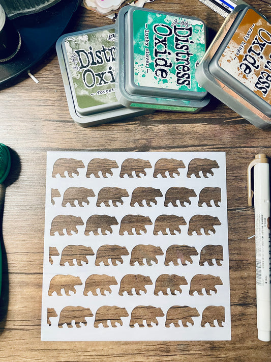 A sheet of die-cut stickers featuring brown bear silhouettes with a distressed wood-grain texture, displayed on a wooden tabletop alongside Distress Oxi ink pads and a white marker.